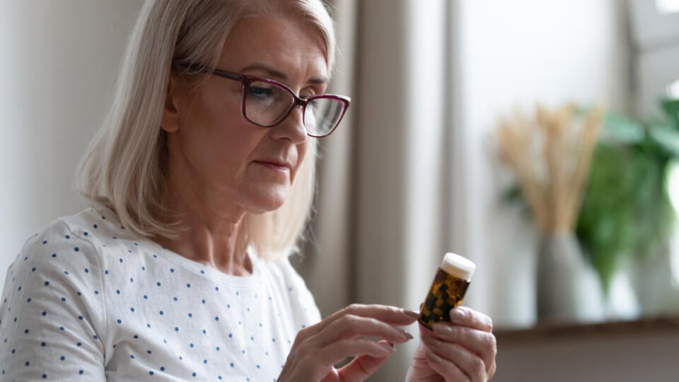 Mature,Woman,In,Glasses,Hold,Bottle,With,Pills,Read,Medicine
