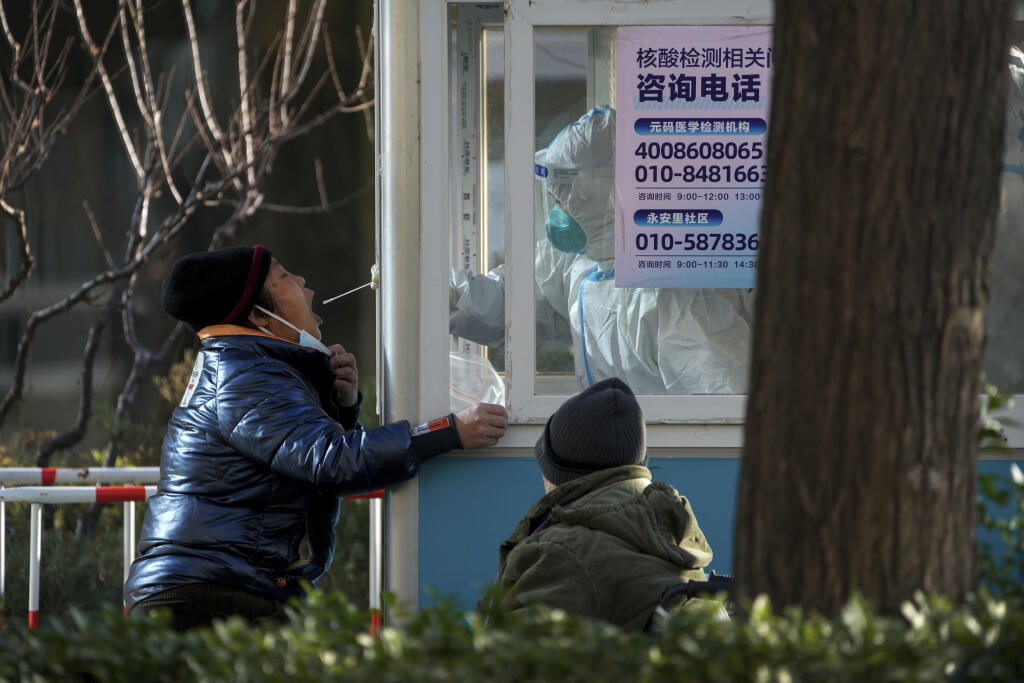 KK12 Peking - Pracovník v ochrannom odeve  testuje miestneho obyvatelia na ochorenie COVID-19 v Pekingu 5. decembra 2022. V Číne by sa už čoskoro mohla zmeniť klasifikácia ochorenia COVID-19 ako vážnej nákazlivej choroby, čo by malo za následok zmiernenie prísnych protiepidemických opatrení. FOTO TASR/AP
A worker in protective gear collects a sample from a resident at a coronavirus testing site in Beijing, Monday, Dec. 5, 2022. China is easing some of the world's most stringent anti-virus contro
