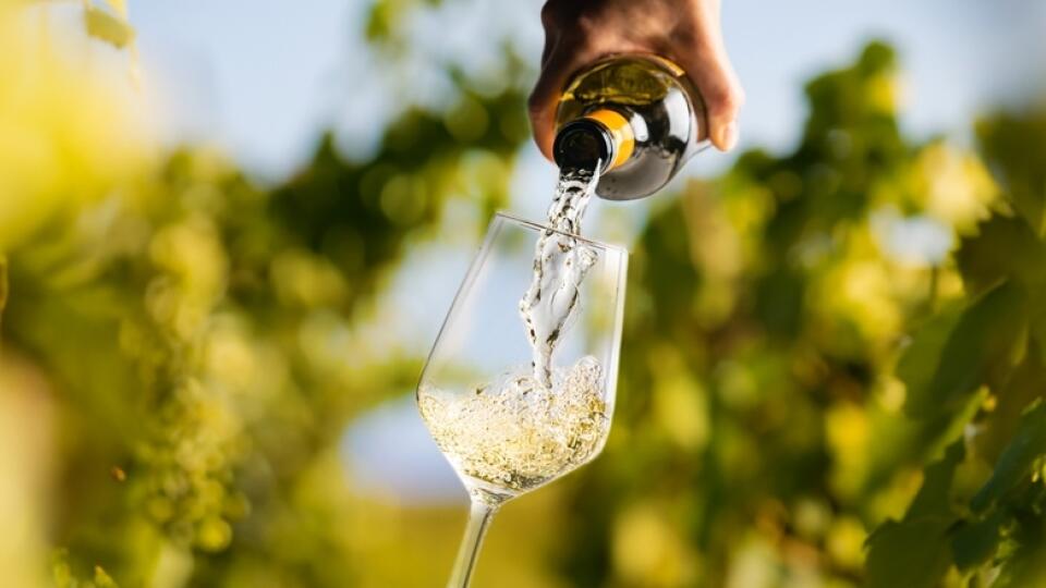 Wine,Glass,With,Pouring,White,Wine,And,Vineyard,Landscape,In