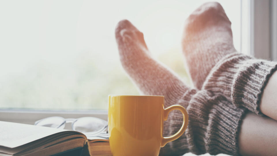 Woman,Resting,Keeping,Legs,In,Warm,Socks,On,Table,With