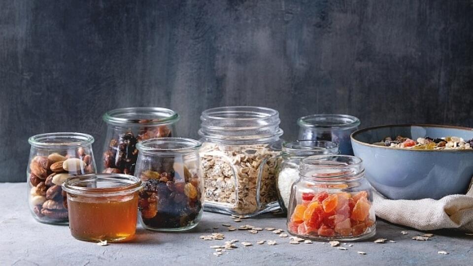 Variety of dried fruits. nuts. honey and oat flakes in bowl and different glass jars for cooking homemade healthy breakfast muesli or granola energy bars on grey blue table. . (Photo by: Natasha Breen/REDA&CO/Universal Images Group via Getty Images)