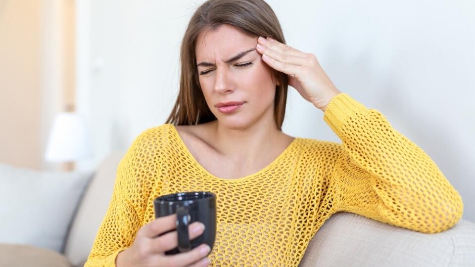 Depressed,Young,Woman,Having,Headache,While,Drinking,Coffee,On,Sofa