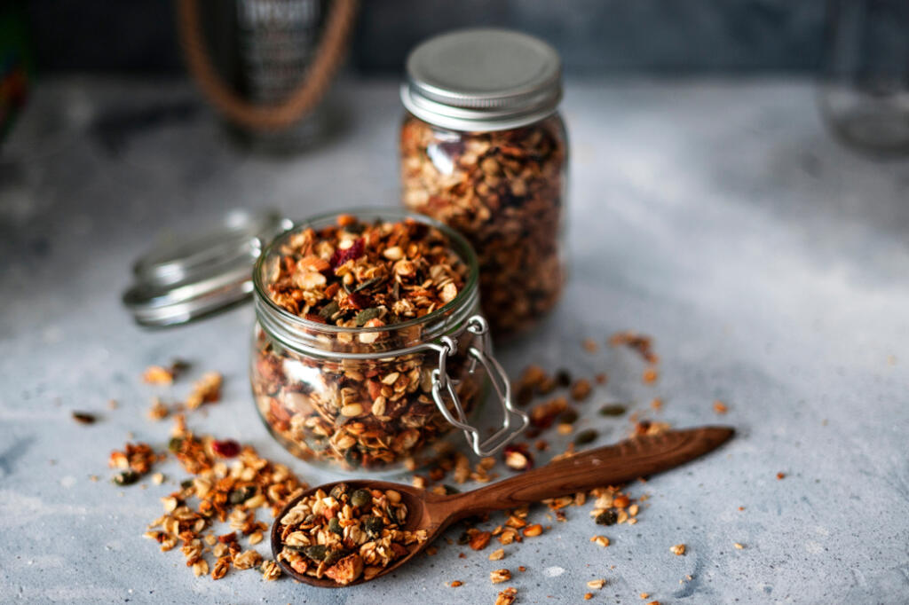 Home granola in a glass jar. Selective focus, concrete background.Healthy vegan snack