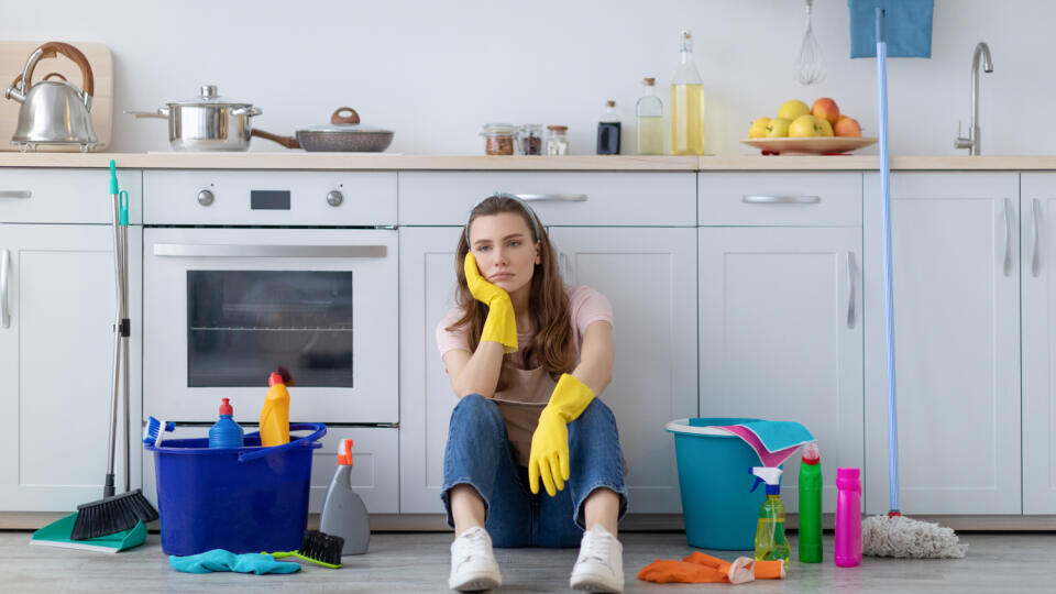 Exhausted,Young,Housewife,Sitting,On,Floor,At,Kitchen,,Surrounded,By