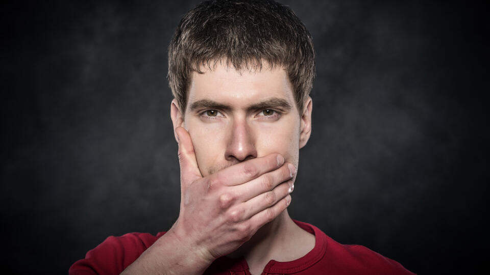 Young,Scared,Man,Hand,Covering,Mouth,Over,Dark,Background.