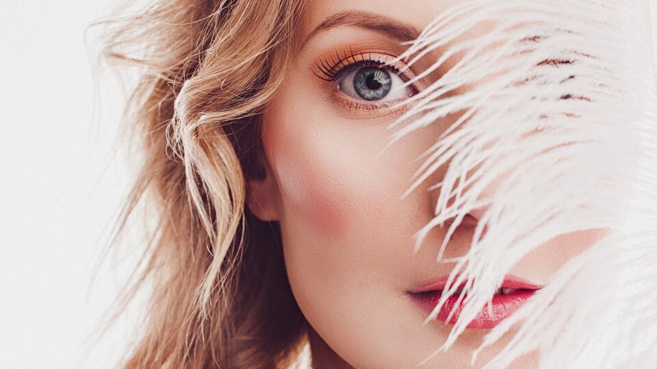 Beautiful young woman with elegant make-up and feather