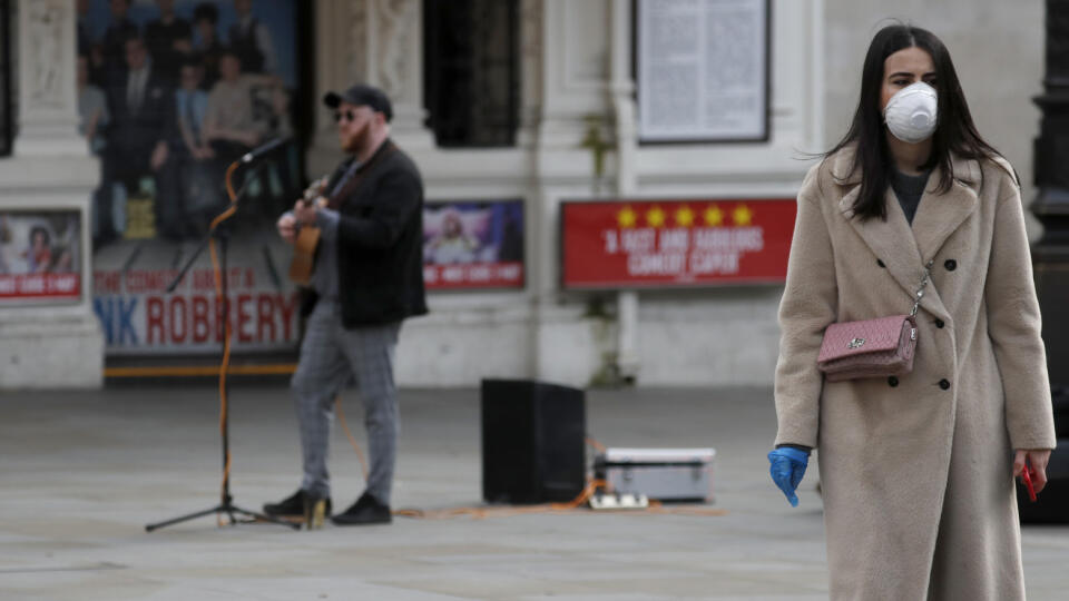 MIK 7 Londýn - Pouličný muzikant vystupuje bez povolenia a žena kráča s ochranným rúškom na Piccadilly Circus v anglickom Londýne 17. marca 2020. Odborníci z londýnskej vysokej školy Imperial College odporučili britskej vláde, aby krajina sprísnila opatrenia v súvislosti s nákazou koronavírusom. FOTO TASR/AP

A street musician performs without ordinance as a woman with a face protection mask passes by at Piccadilly Circus after coronavirus outbreak in London, Tuesday, March 17, 2020. For most pe