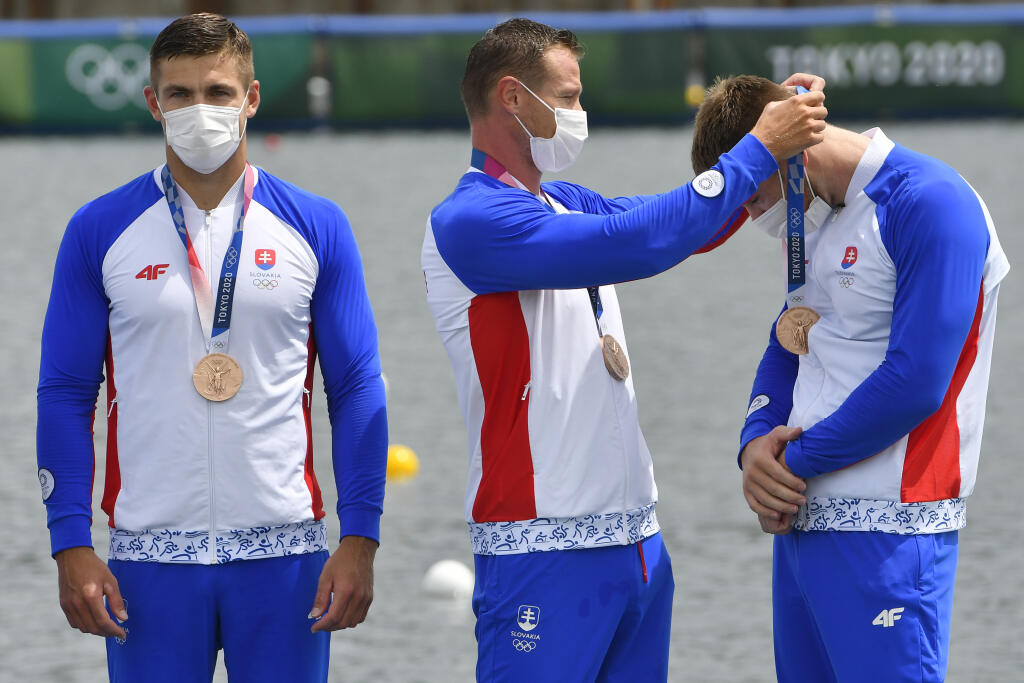 Na snímke slovenská posádka rýchlostných kanoistov K4 v zložení Samuel Baláž, Denis Myšák, Erik Vlček a Adam Botek získala bronzovú medailu na 500 metrov počas XXXII. letných olympijských hier v Tokiu, 7. augusta 2021. Na snímke Erik Vlček dekoruje Adama Boteka, ktorú im priniesla Danka Barteková počas medailového ceremoniálu, vľavo Denis Myšák. FOTO TASR - Michal Svítok