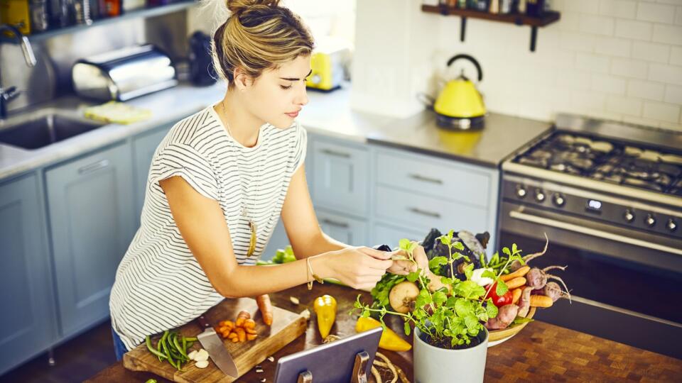 Young woman picking mint leaves at kitchen island