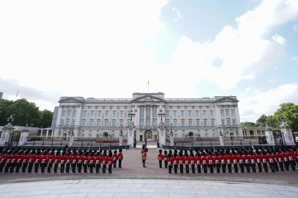 ríslušníci vojenského pluku Coldstream Guards stoja pred Buckinghamským palácom pred slávnostnou procesiou s prevozom rakvy s telesnými pozostatkami zosnulej britskej kráľovnej Alžbety II. z Buckinghamského paláca do Westminsterského paláca v Londýne 14. septembra 2022.