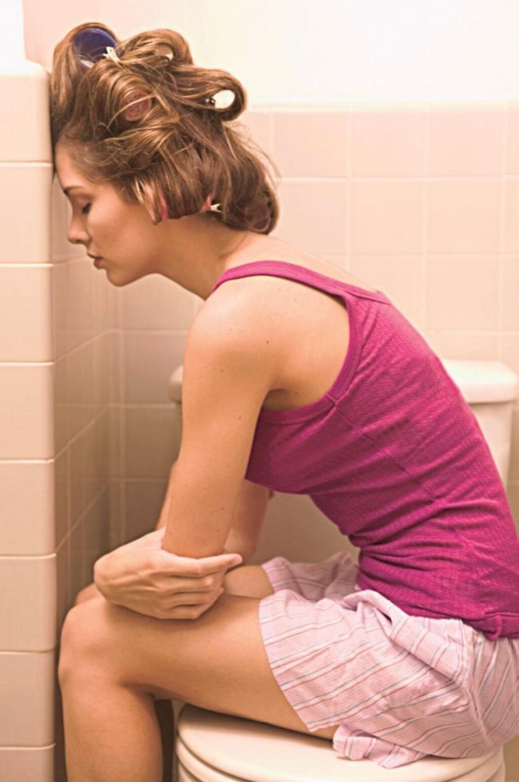 Болит низ живота и частое мочеиспускание. У девушки диарея. Женщина сидит в туалете.