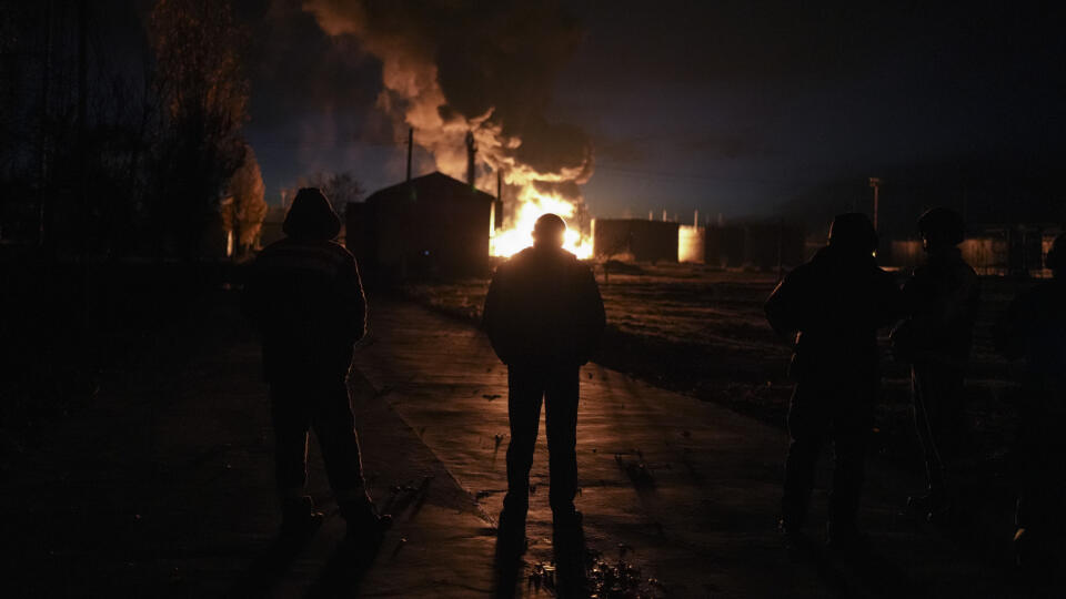 Na snímke ľudia sledujú stúpajúci dym stúpa a plamene požiaru, ktorý vypukol po ruskom útoku v ukrajinskom Chersone 19. novembra 2022. FOTO TASR/AP