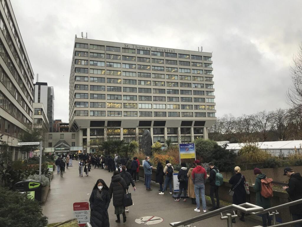 Ľudia stoja v rade na očkovanie treťou posilňujúcou dávkou vakcíny proti ochoreniu COVID-19 pred nemocnicou St Thomas Hospital v Londýne 13. decembra 2021.