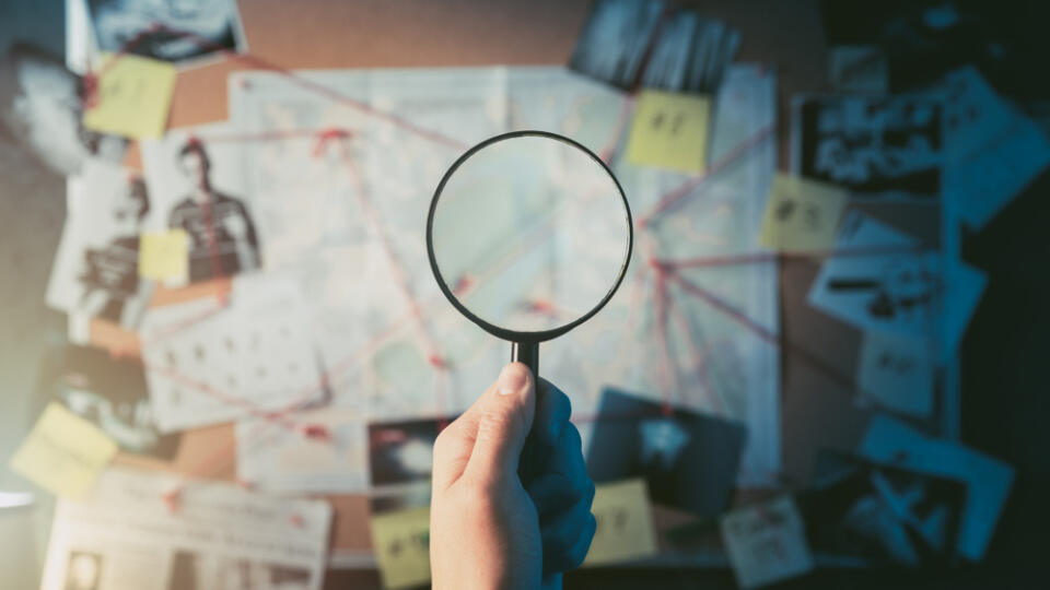 Detective,Hand,Holding,A,Magnifying,Glass,In,Front,Of,A