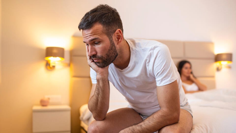 Young,Sad,Man,Sitting,On,Bed,After,Quarrel,With,Wife.