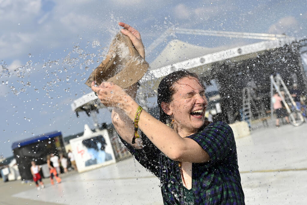 Návštevníčka sa ochladzuje vodou počas otváracieho dňa série piatich festivalov so spoločným názvom Pohoda on the Ground, 7. júla 2021 na letisku v Trenčíne. FOTO TASR - Radovan Stoklasa