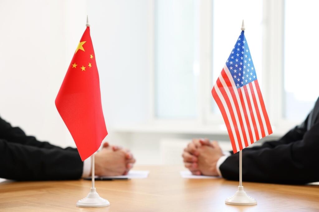 Diplomats,Negotiating,During,Meeting,At,Table,Indoors,,Focus,On,Flags