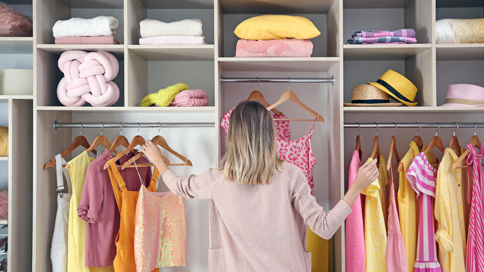 Woman choosing clothes from large wardrobe closet