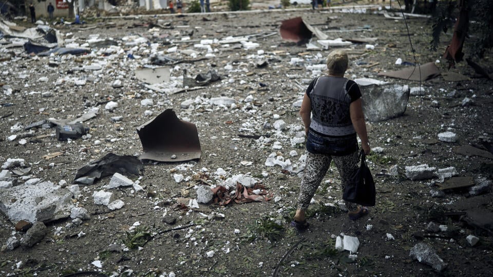 Žena kráča okolo budovy zničenej pri nočnom bombardovaní v Mykolajive na juhu Ukrajiny 3. augusta 2022.