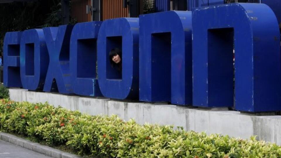 Zamestnankyňa sa pozerá cez logo elektronického gigantu Foxconn