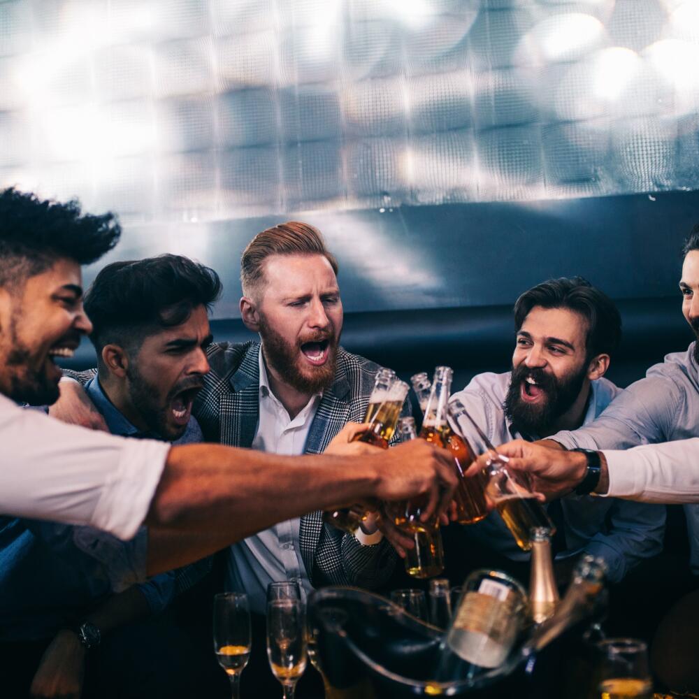 Group of young men toasting with beer at a nightclub