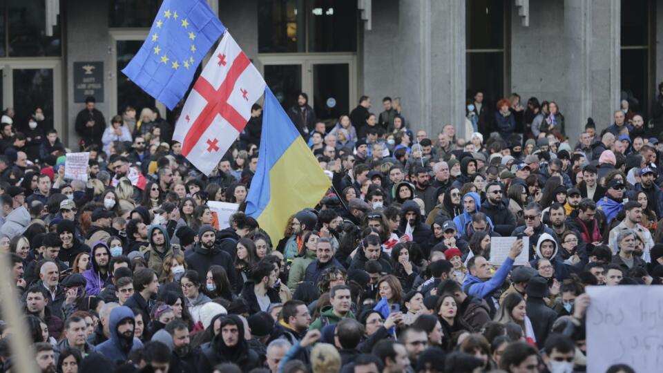 Protestujúci sa zhromažďujú s americkými, gruzínskymi, ukrajinskými vlajkami a vlajkami EÚ pred budovou gruzínskeho parlamentu 8. marca 2023 v Tbilisi. Gruzínska polícia nariadila v stredu večer rozchod tisíckam demonštrantov, ktorí sa zhromaždili v hlavnom meste Tbilisi na protest proti spornému návrhu zákona o