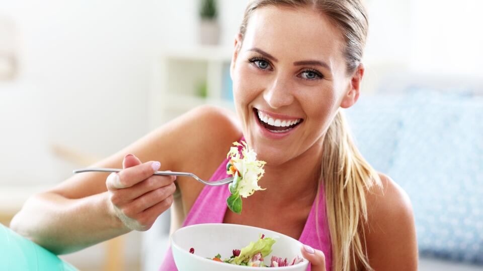 Young woman eating healthy salad after workout