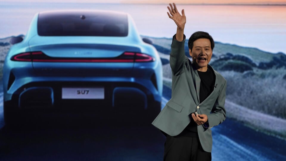Zakladateľ Xiaomi Lei Jun mávne rukou po predstavení SU7, športového štvordverového sedanu v Pekingu.