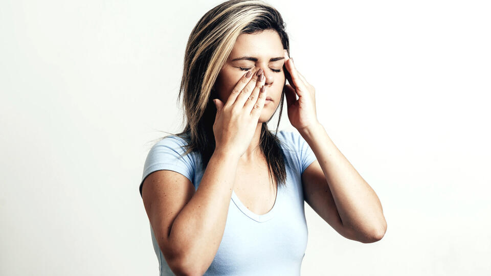 Sinus pain, sinus pressure, sinusitis. Sad woman holding her nose and head because sinus pain