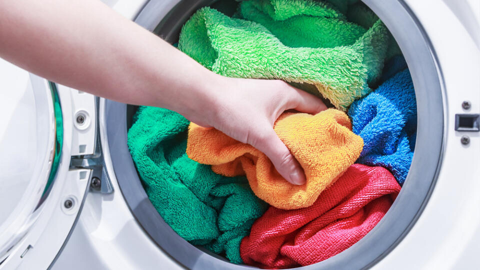 Hand,And,Puts,The,Laundry,Into,The,Washing,Machine.,Focus