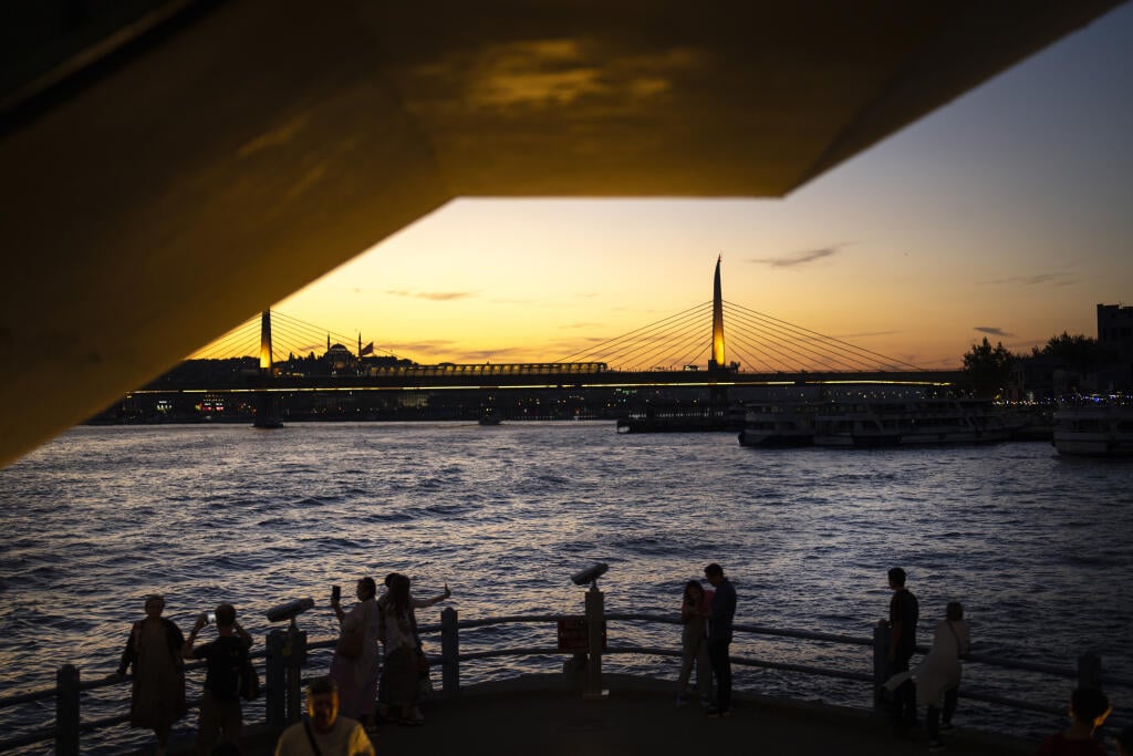 Ľudia fotografujú na moste Galata pri západe slnka v Istanbule v Turecku.