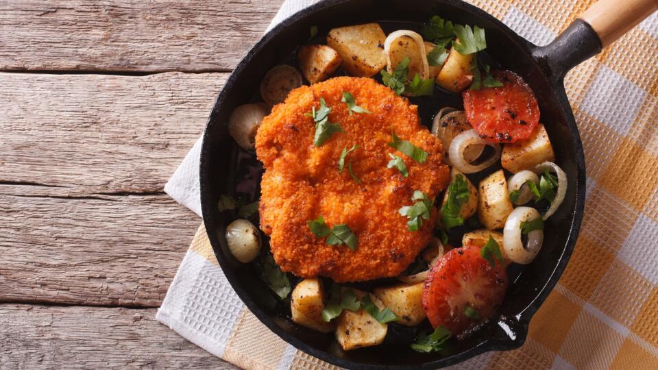 German Weiner schnitzel with vegetables in pan. horizontal top view