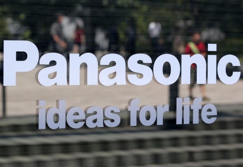 People are reflected on a glass exterior of a Panasonic showroom in Tokyo Tuesday, July 31, 2012. Consumer electronics giant Panasonic Corp. said Tuesday it returned to the black in the April-June quarter, logging a net profit of 12.8 billion ($163 million) mainly on lower costs after cutting more than 38,000 jobs over the last year. (AP Photo/Itsuo Inouye)