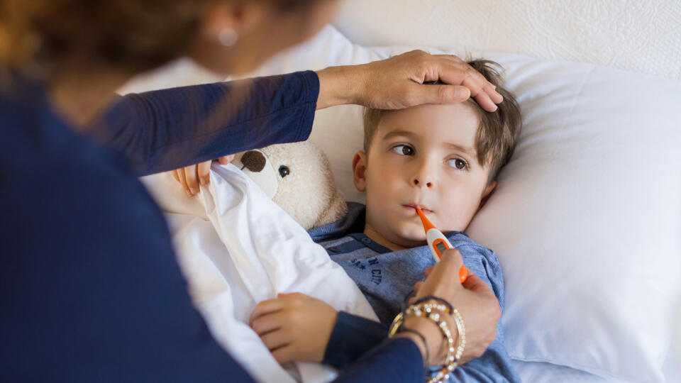 Sick,Boy,With,Thermometer,Laying,In,Bed,And,Mother,Hand