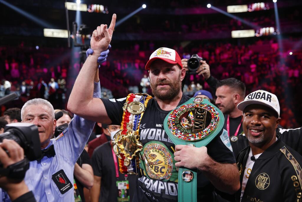 Britský boxer Tyson Fury (uprostred) sa teší zo zisku titulu majstra sveta organizácie WBC 9. októbra 2021 v Las Vegas. Britský boxer Tyson Fury obhájil titul majstra sveta organizácie WBC. V noci na nedeľu v Las Vegas knockoutoval Američana Deontaya Wildera v 11. kole.