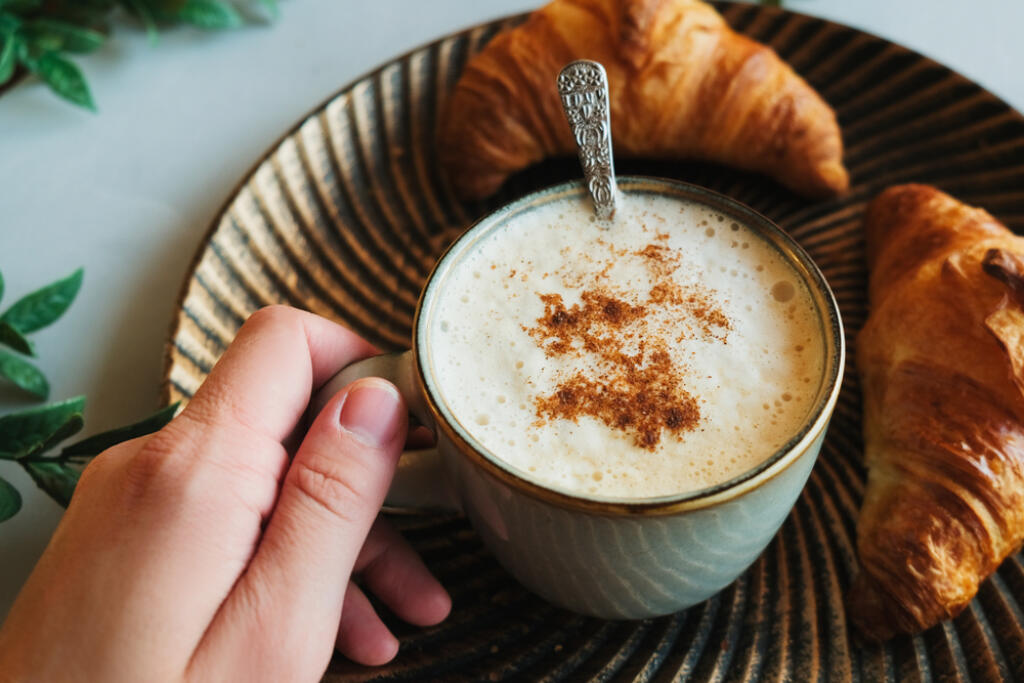 Female,Hand,Holds,Cappuccino,Coffee,Sprinkled,Cinnamon,,Fresh,Pastries,On
