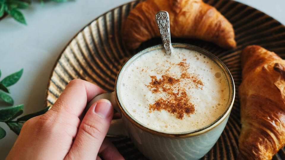 Female,Hand,Holds,Cappuccino,Coffee,Sprinkled,Cinnamon,,Fresh,Pastries,On