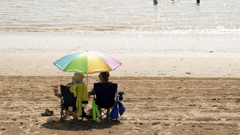 Ľudia sedia na pláži počas teplého počasia na ostrove Barry Island vo Walese 6. septembra 2023.