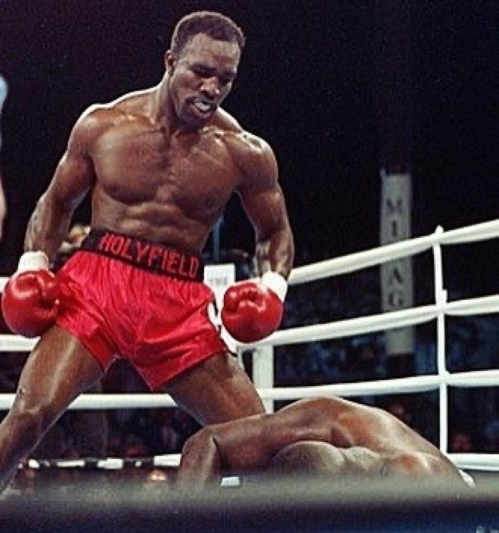 Evander Holyfield sa skláňa nad Foremanom, ktorého poslal k.o. úderom k zemi v 7. kole.