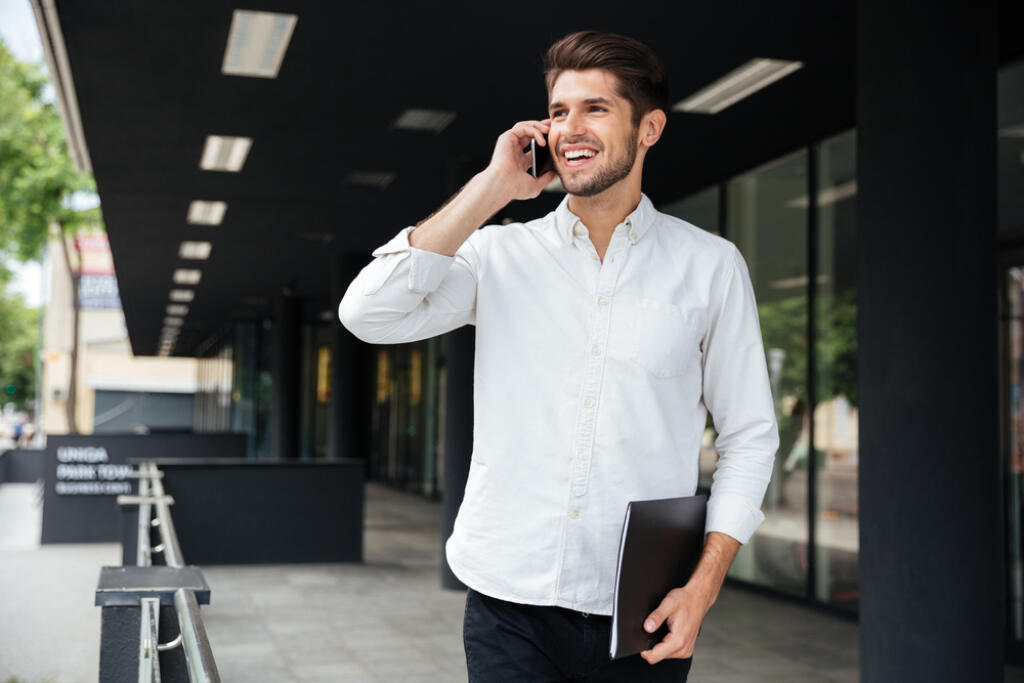 Happy,Young,Businessman,With,Folder,Walking,And,Talking,On,Cell