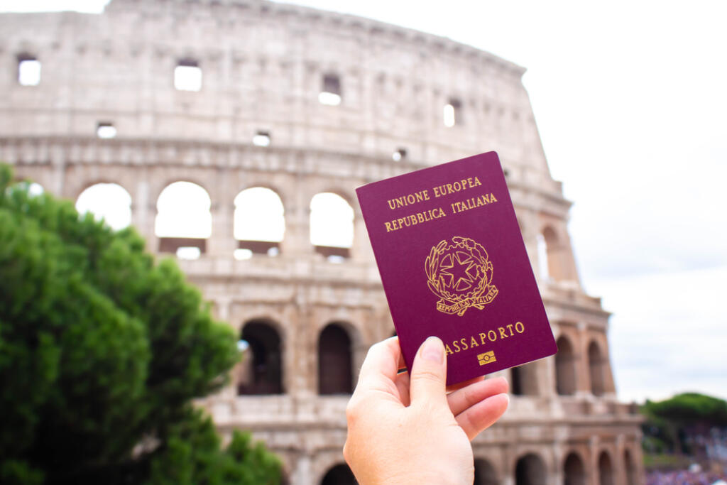 Italian passport in hand against the background of the Coliseum, Rome Italy