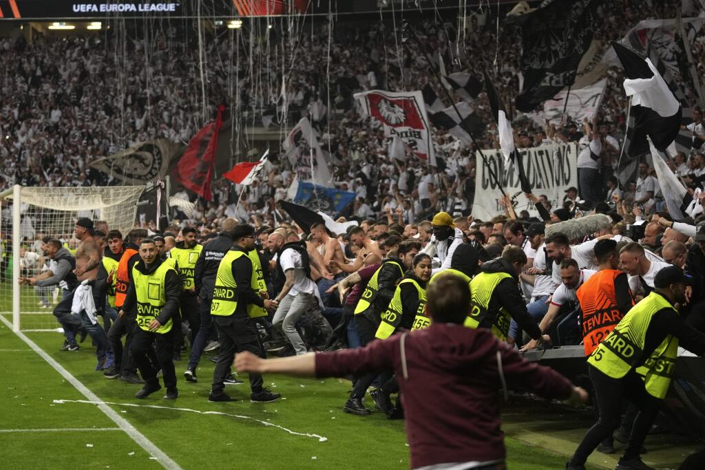 Bezpečnostní pracovníci zastavujú fanúšikov Frankfurtu, ktorí vtrhli na ihrisko po postupe do finále v odvete semifinále Európskej ligy Eintracht Frankfurt - West Ham United vo Frankfurte 5. mája 2022.