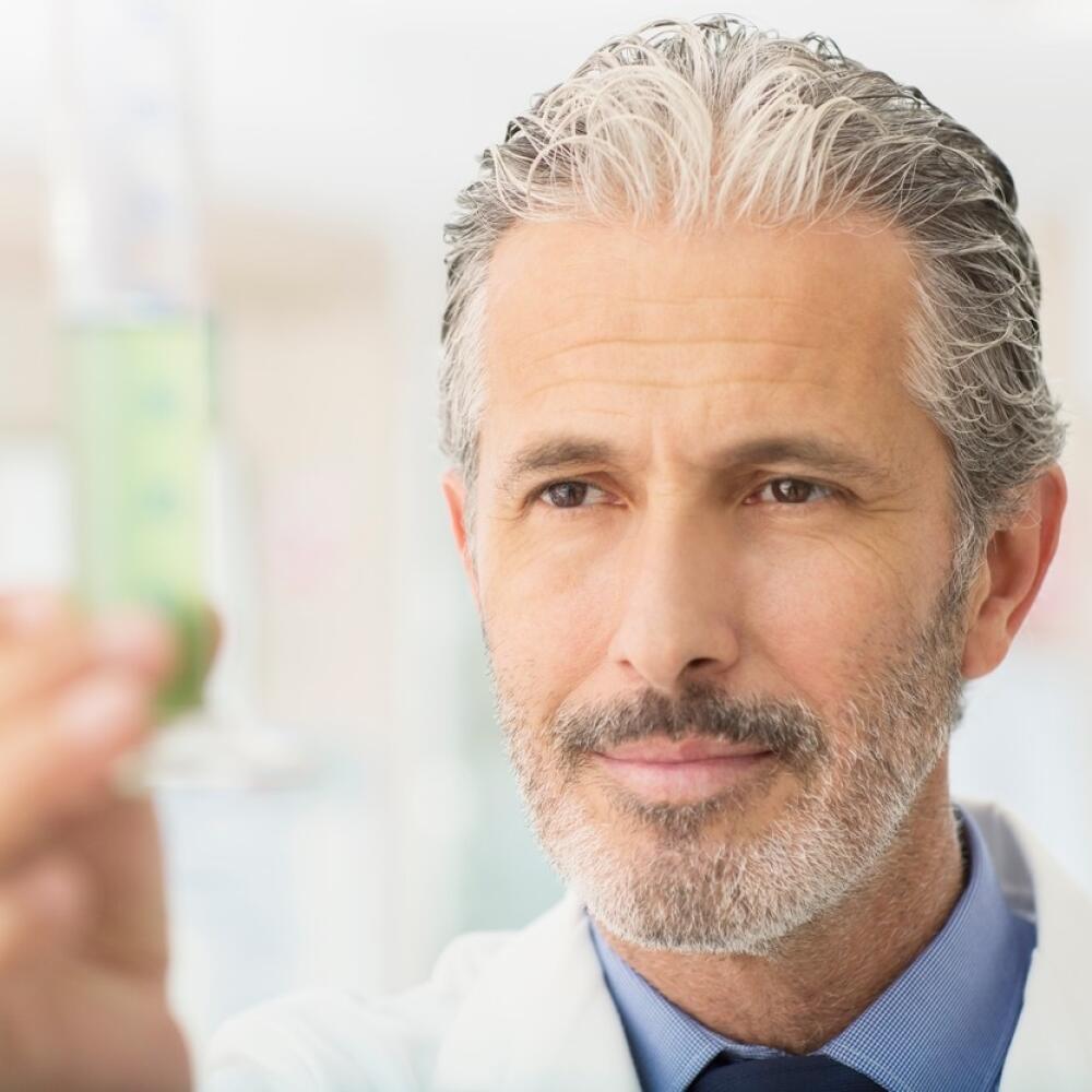 Scientist examining green liquid in tube