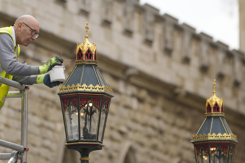 Maliar premaľováva lampu pred Westminsterským opátstvom počas príprav na korunováciu britského kráľa Karola III. v Londýne 27. apríla 2023.