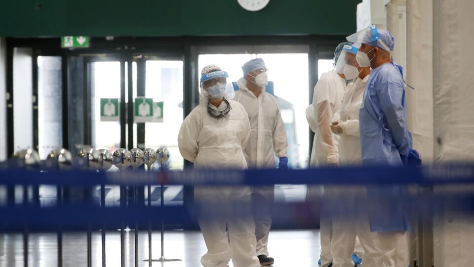 Talianski zdravotníci v ochranných odevoch a s ochrannými štítmi na zabránenie šíreniu nového koronavírusu čakajú na pasažierov prichádzajúcich z rizikových stredomorských krajín počas testovania na ochorenie COVID-19 na letisku Malpensa v Miláne.