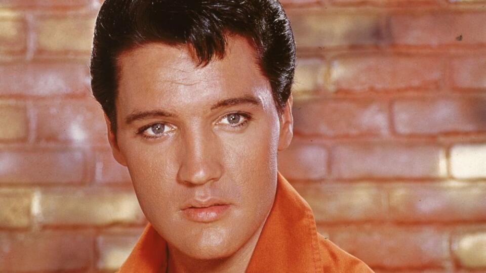 Portrait of American rock and roll singer Elvis Presley, dressed in an orange open-neck shirt and in front of a brick wall, mid 1960s. (Photo by Hulton Archive/Getty Images)