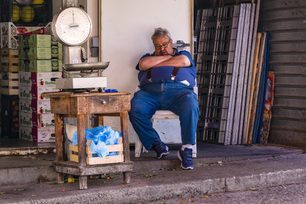 A vendor takes a nap in front of his shop at the local