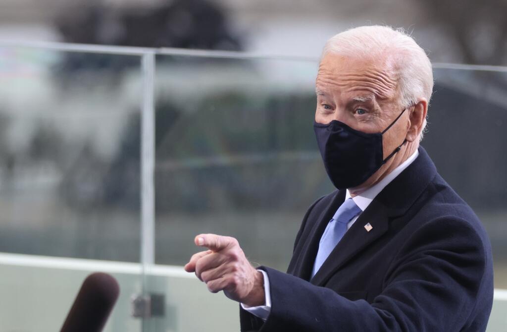 Joe Biden s ochranným rúškom gestikuluje počas príchodu na inauguráciu.