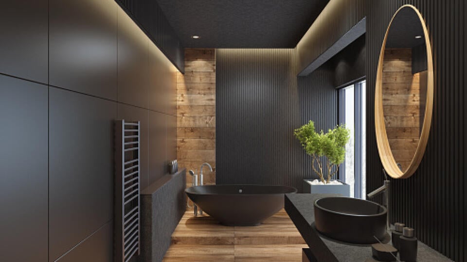 contemporary minimalist bathroom with black wooden walls and large grey matte and wood effect tiles. 
round mirror with wooden frame is on the wooden black wall. 
round grey stone washbasin and stainless steel basin tap is on top of the grey stone vanity unit with three drawers.
freestanding black stone bathtub and floor mounted inox tap is on a platform with wood effect tiles. 
long floor tiles with wood effect. black ceiling with strip cove lighting and embedded spotlights.

***background is m