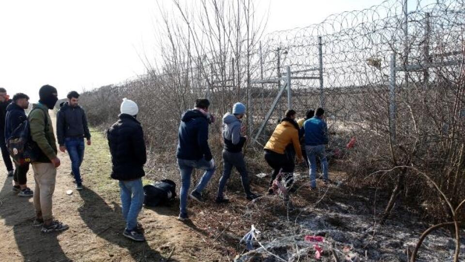 Na snímke migranti sa pokúšajú prestrihnúť oplotenie na turecko-gréckej hranici v blízkosti hraničnej brány Pazarkule v tureckom meste Edirne 2. marca 2020.